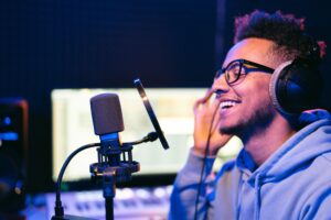 A young man looks happy while recording voiceovers with a professional voiceover microphone and studio equipment.